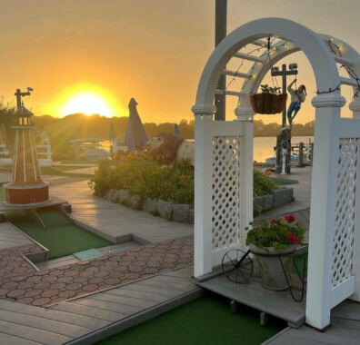 'Puff N' Putt Mini Golf course with the sun setting over Fort Pond in the background