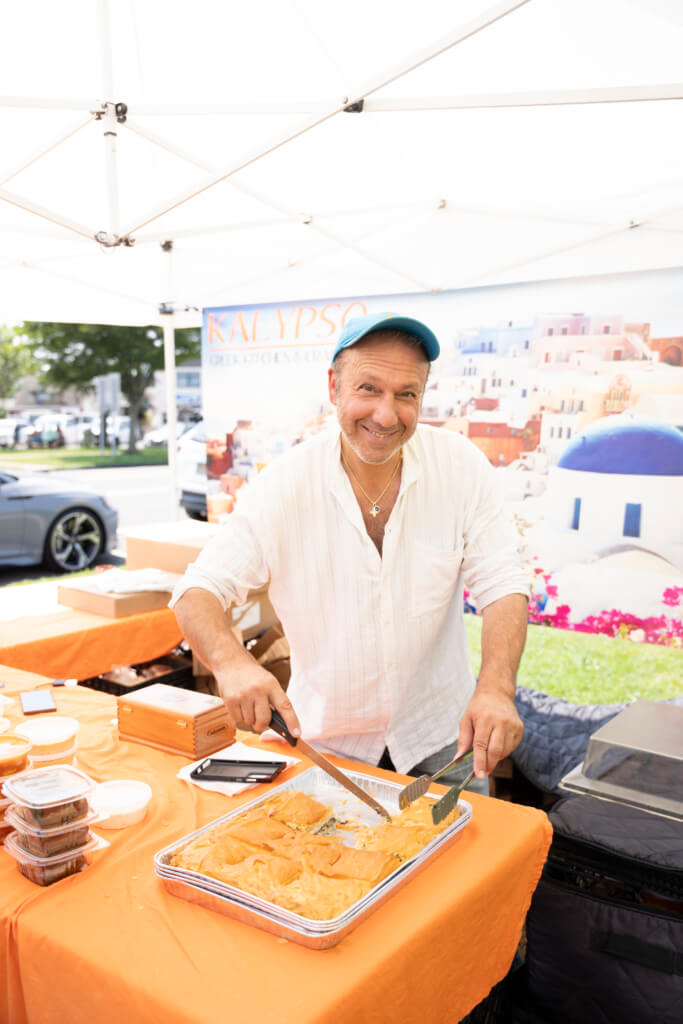 Nicholas Trastelis poses with fresh products in his Kalypso Greek Yogurt Farmers Market Booth