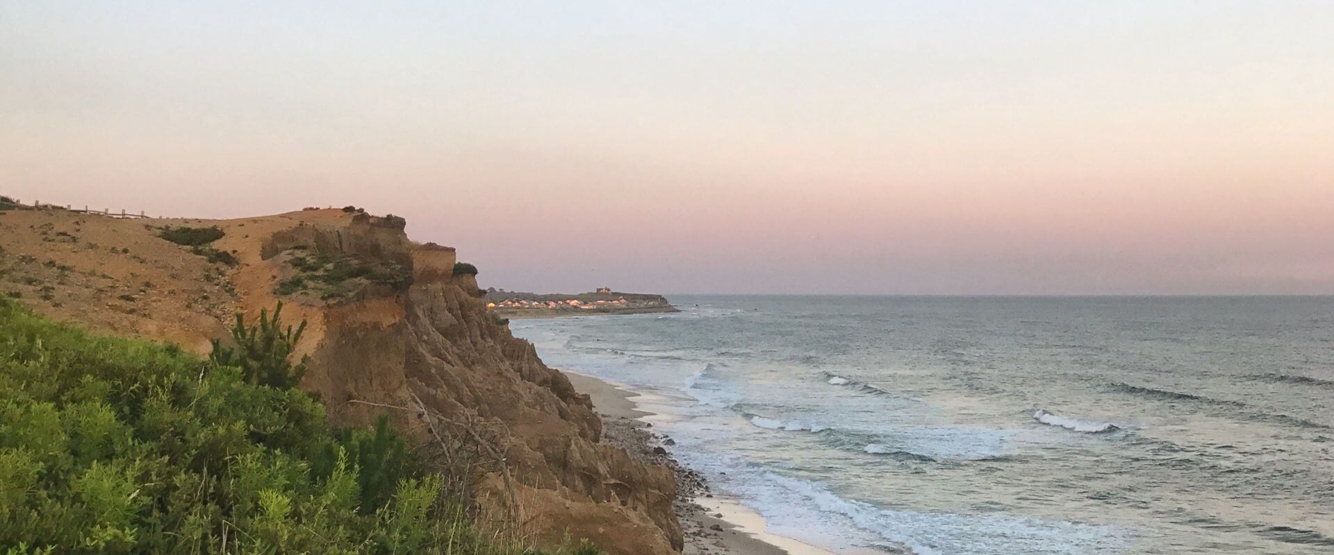 Image of Montauk bluffs and coast, with sunrise hues in the background